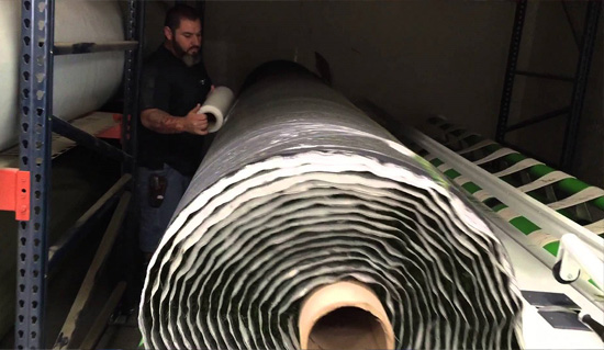 Accu-Cut Machine wrapping large roll of artificial turf.